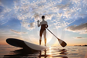 Stand-up paddle, paddle standing, silhouette of man on the beach photo