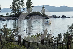 Stand up paddleboard floating and boats anchored near a beach at sunset in lake tahoe