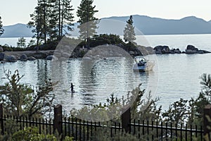 Stand up paddleboard floating and boats anchored near a beach at sunset in lake tahoe