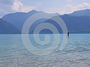 Stand up paddler on a clear blue moutain lake in Austria