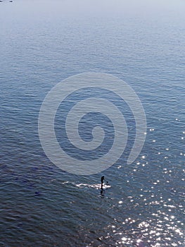 Paddle boarder alone in the vast ocean photo