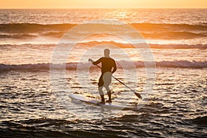 Stand up paddler silhouette at sunset