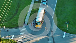 Standard American yellow school bus picking up kids at rural town street stop for their lessons in early morning. Public