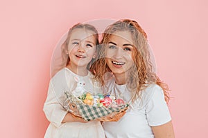 Standing against pink background. Happy mother and daugher celebrating Easter holidays together