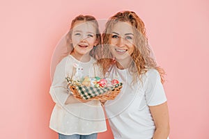 Standing against pink background. Happy mother and daugher celebrating Easter holidays together