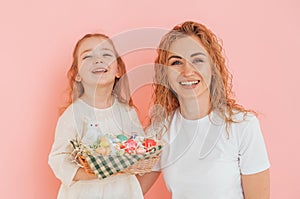 Standing against pink background. Happy mother and daugher celebrating Easter holidays together