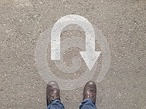 Standing on the asphalt concrete floor in front of u turn symbol
