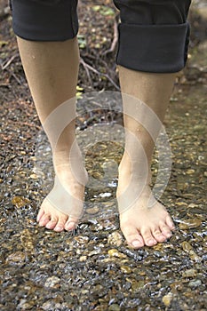 Standing barefooted in a shallow stream