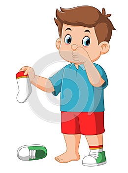 Standing boy kid holding dirty smelling sock in hand closing nose