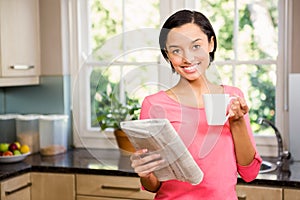 Standing brunette holding cup and newspaper