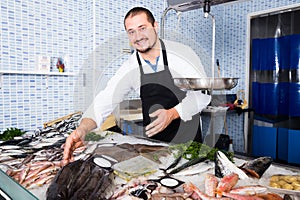 Standing cheerful man shows the fish counter photo