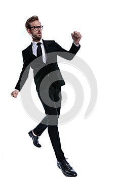 Standing elegant man in black suit holding fists up