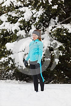 Standing girl wearing winter sportswear, trees background