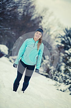 Standing girl wearing winter sportswear, trees background
