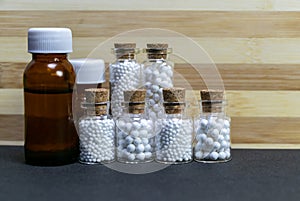 Standing homeopath medicine bottles in a row on wood and dark background photo