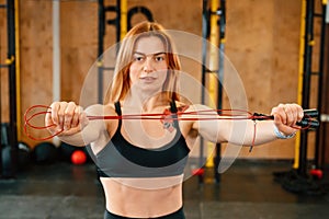 Standing with jump rope. Beautiful strong woman is in the gym