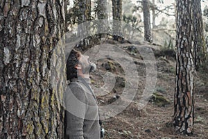 Standing man enjoying happiness and joyful feeling the outdoors nature park against a pine tree trunk. People and forest woods