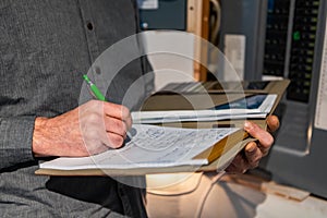 Standing man writes on notebook