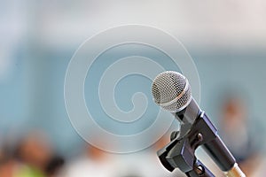 Standing microphone for speaker`s speech in the seminar room with audience in the background