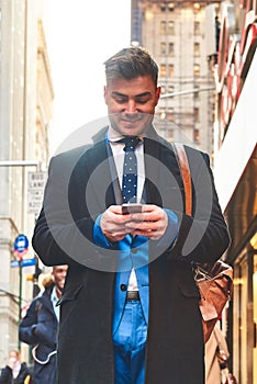 Standing by myself in a different world. Shot of a cheerful young man texting on his cellphone while standing in the