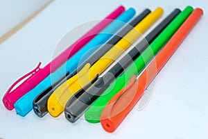 Standing Out From The Crowd Concept. Bunch of assorted multi colored boll point pens in rainbow arrangement on white background,