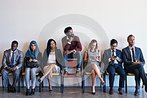 Standing out of the crowed. a group of confident businesspeople waiting in line for their interviews while a man sits on