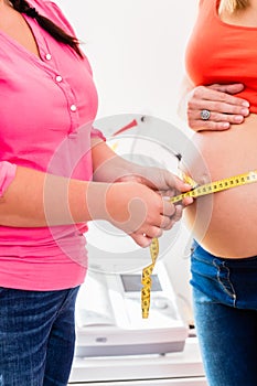 Standing pregnant women and midwife measuring circumference of b photo