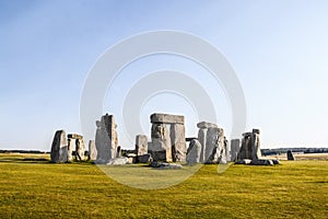 Standing rocks of ancient Stonehenge with defining shadows under clear blue sky on bright summer morning standing alone on