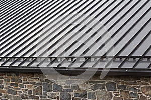 Standing seam modern metal roof over vintage stone wall