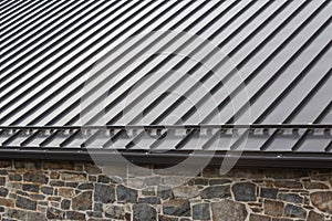 Standing seam modern metal roof over vintage stone wall photo