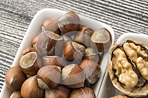 Standing side by side in separate plate of shelled hazelnuts and shelled walnuts pictures