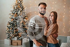 Standing and smiling. Lovely young couple are celebrating New Year at home