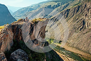 Standing sporty man with backpack on the mountain peak and beautiful mountains atbright sunny day.