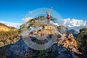 Standing at the top of a rocky cliff arms outstretched achievement