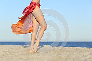 Standing woman legs posing on the beach wearing a pareo