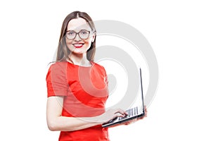 Standing young adult woman in red dress & glasses holding laptop computer - i