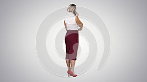 Standing young beautiful woman using a mobile phone making a call on gradient background.