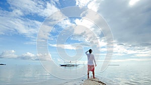 Standing young man looks at horizon on beach