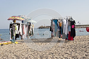 Stands selling garments and sundresses on the shore at the beach.