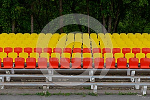 Stands of a small stadium with rows of yellow and red seats