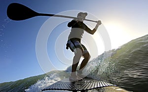Standup paddle board surfing a wave at sunrise