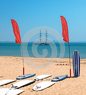 Standup Paddle boards on beach with bokeh caravel in background