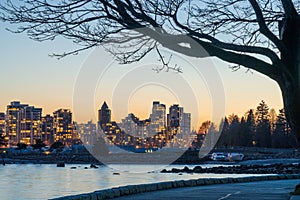 Stanley Park Seawall in dusk. Vancouver downtown skyline in the background. Canada.