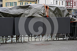 Stapled chairs and tables of a  closed terrace restaurant partly covered with tarpaulin in Lucerne, Switzerland.