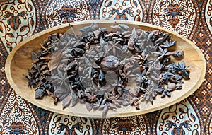 Star anise and dried nutmeg on a wooden plate can be utilized as interior design elements that create an exotic and warm ambiance. photo