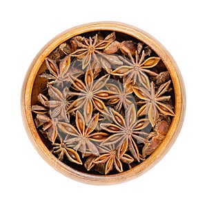 Star anise fruits and seeds, pericarps of Illicium verum, in wooden bowl photo