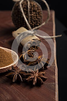 Star anise, ground nutmeg, cloves in a pomander and cinnamon quills on a wooden board