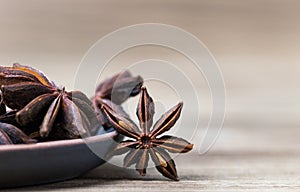 Star anise with and without seeds, in a clay dish on a light wooden surface. spice for cooking, medicine, cosmetics. background photo