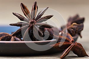 Star anise with and without seeds, in a clay dish on a light wooden surface. spice for cooking, medicine, cosmetics. background photo