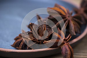 Star anise with and without seeds, in a clay dish on a light wooden surface. spice for cooking, medicine, cosmetics. background photo